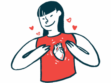 A woman smiles while gesturing with two hands toward the image of a human heart on her red sleeveless shirt.