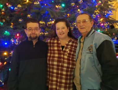 post-transplant | Pulmonary Hypertension News | Cullen stands with his mother and grandfather in front of a Christmas tree at Immaculata University's Carol Night event.