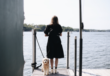 dog | Pulmonary Hypertension News | Anna stands on a dock looking out over the water while her dog, Luna, stands by her side.