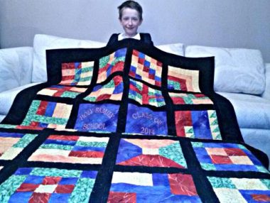 Pulmonary Hypertension News | Cullen sits in a bed and is covered by a beautiful and colorful quilt that his eighth-grade classmates made for him in 2014. 
