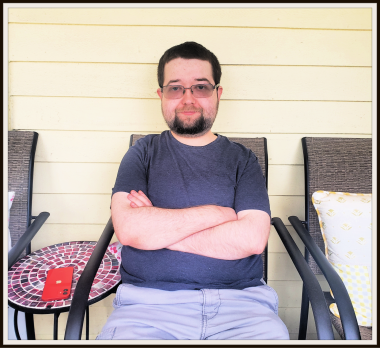 transplant anniversary | Pulmonary Hypertension News | Cullen, 22, sits with arms folded on an outdoor patio chair next to the house. He wears semi-dark tinted glasses and a goatee