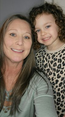 A close-up vertical selfie shows a smiling woman with long, blond hair next to a smiling 4-year-old girl wearing a leopard-print shirt or nightgown.