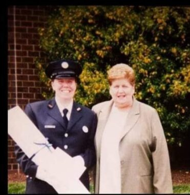 A blurry photo taken from a camera in 2003 shows a young white woman and her mother standing in front of a tree. The young woman on the left is dressed in a Philadelphia Fire Department Academy uniform. The mother, on the right, wears a tan coat and a white blouse. 