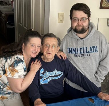 A man smiles as his daughter and grandson stand on either side of him to celebrate his 95th birthday.