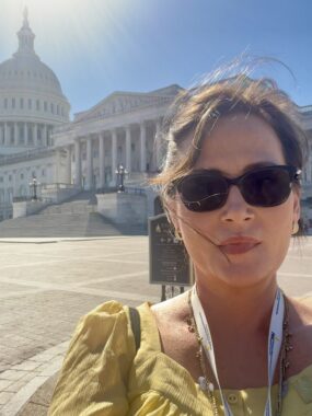 A closeup image of a woman standing in front of the U.S. Capitol.